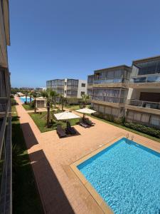 a swimming pool in front of a building with umbrellas at Odyssée Atlantique Blue beach - Sidi Rahal - famille seulement in Sidi Rahal