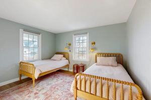 two beds in a room with two windows at Ledge on Green in Rockport