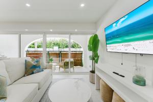 a living room with a white couch and a flat screen tv at The Mizner Pool Suite - Boca Beachside in Boca Raton