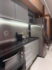 a kitchen with a sink and a stainless steel refrigerator at V-Home Flat Hotel in Macaé