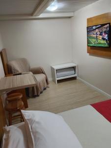 a bedroom with a bed and a tv on the wall at Morada Bem Me Quer in Canela