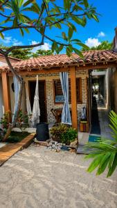 a house with a porch with curtains on it at Beach House Suítes Jeri in Jericoacoara