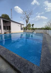 a swimming pool with blue water in front of a building at Rainbow Cottage Stays in Kānha