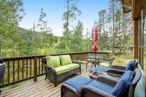 a deck with chairs and a table and a umbrella at Alpine Holidays Ski Tip in Keystone