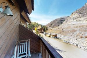 a chair on a balcony with a view of a river at Bellflower Trout House in Vail