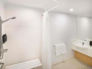a white bathroom with a shower and a sink at Mercure Sydney Macquarie Park in Sydney +50 photos