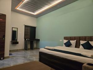 a bedroom with a large bed with blue pillows at Rainbow Cottage Stays in Kānha +18 photos