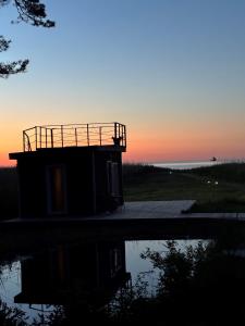 a building with a reflection in the water at sunset at Angervaksa LoodusSpa in Laugu