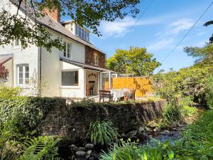 a white house with a stone wall and a garden at Glen Cottage Porlock in Porlock