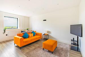 a living room with an orange couch and a flat screen tv at Stylish Central Location Apartment in Norwich