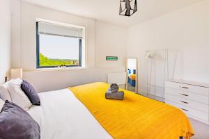 a bedroom with a bed with a yellow blanket and a window at Stylish Central Location Apartment in Norwich