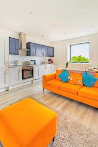 a living room with an orange couch and a kitchen at Stylish Central Location Apartment in Norwich