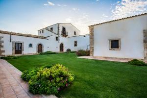 uma grande casa branca com um jardim verde em Casal Sikelio em Cassibile