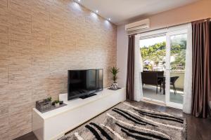 a living room with a flat screen tv on a brick wall at Margaritum Blace - Seaview Apartment with Balcony in Blace