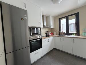 a kitchen with white cabinets and a stainless steel refrigerator at FoFo Apartamento 78 in Cijuela