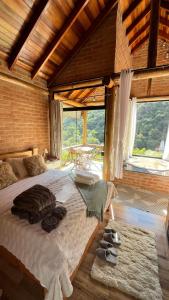 a bedroom with a large bed with a large window at Chales Estância Verdejante in Sapucaí-Mirim