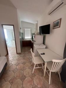 a room with a table and chairs and a refrigerator at Residence La Beloutiere in Porto-Vecchio