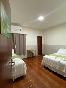 a room with two beds and a table in it at Pousada Casa Grande in Barra do Garças
