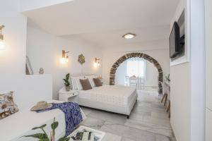 a white living room with a bed and a tv at Hotel Anixis in Naxos Chora