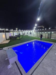 a swimming pool at night with a person standing next to it at شاليه روز حتا - Hatta Rose Chalet in Hatta