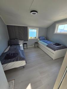 a bedroom with two beds and two windows at Oldervik Sea House in Tromsø