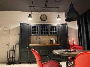 a kitchen with black cabinets and a table with red chairs at The secret room in Alba Iulia