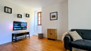 a living room with a couch and a tv at Maison rénovée, centre médiéval de Belvès in Belvès