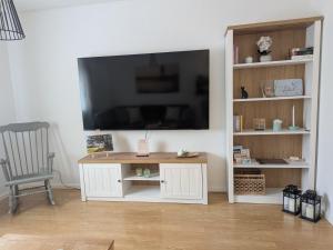 a living room with a white entertainment center with a flat screen tv at Gute Stube - Ferienhaus NaheZeit Bostalsee in Nohfelden +17 photos