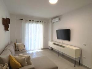 a living room with a couch and a flat screen tv at Sunshine Apt Qerret-Golem Beach-Self-Check-in in Golem