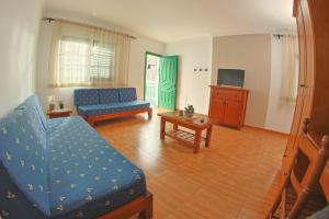 a living room with a blue couch and a tv at Apartamentos La Palmera in Frontera
