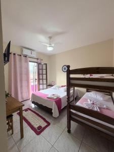 a bedroom with two beds and a table and a window at Casa Carol Vans in Peruíbe