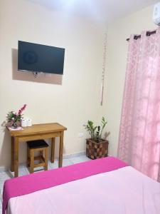 a bedroom with a bed and a table and a tv at Casa Carol Vans in Peruíbe