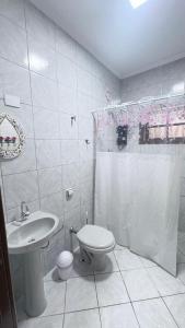 a white bathroom with a toilet and a sink at Casa Carol Vans in Peruíbe +34 photos