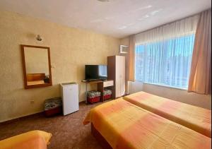 a hotel room with a bed and a television at Guest House Georgieva Ravda in Ravda
