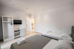 a white bedroom with a bed and a television at Hotel Fabio in Ksamil