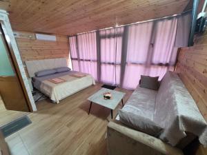 a bedroom with a bed and a couch in a room at Visi Cabins Bogë in Bogë