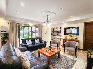 a living room with a leather couch and a table at Falcon Guest House in Harare