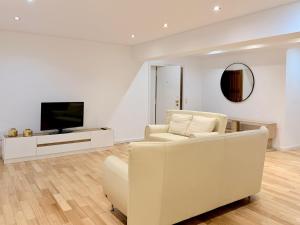 a white living room with a white couch and a tv at Mouzinho Living Centro & Mar in Póvoa de Varzim