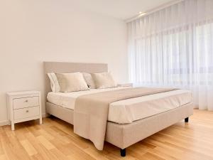a white bedroom with a large bed and a window at Mouzinho Living Centro & Mar in Póvoa de Varzim