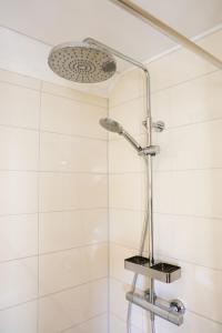 a shower in a bathroom with white tiles at Schuurtje bij de IJssel in Terwolde +19 photos