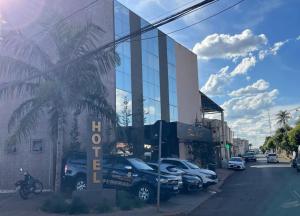 a building with cars parked in a parking lot at Éden Hotel in Rio Verde