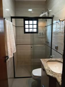 a bathroom with a shower and a toilet and a sink at Pousada Brisa da Mata in Londrina