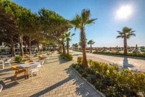 a patio with tables and chairs and palm trees at Sunshine Apt Qerret-Golem Beach-Self-Check-in in Golem