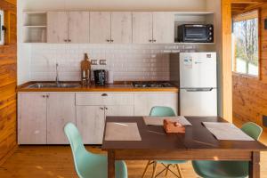 a kitchen with a wooden table and green chairs at Petricor Ecolodge Cab2 in Pucón