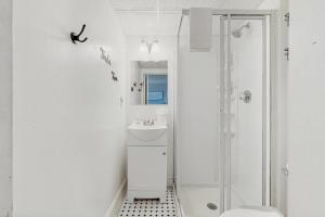 a white bathroom with a shower and a sink at Salty Breeze Studio in Wells +28 photos