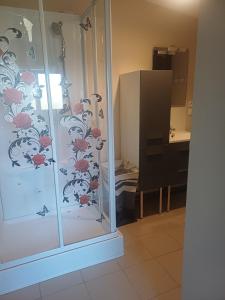 a glass shower door with a floral shower curtain at Studio a la campagne in Dissay