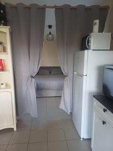 a small kitchen with a bed and a white refrigerator at Studio a la campagne in Dissay +1 photo