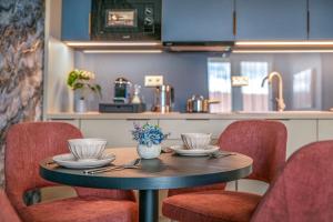 a table with chairs and a table with plates and bowls at Lazuli Apartment in Hegykő