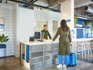 a woman with a suitcase standing at a counter at ibis budget Nancy Laxou in Nancy