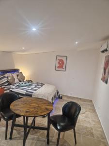 a bedroom with a bed and a table and chairs at Petit appartement avec jacuzzi in Bédarrides